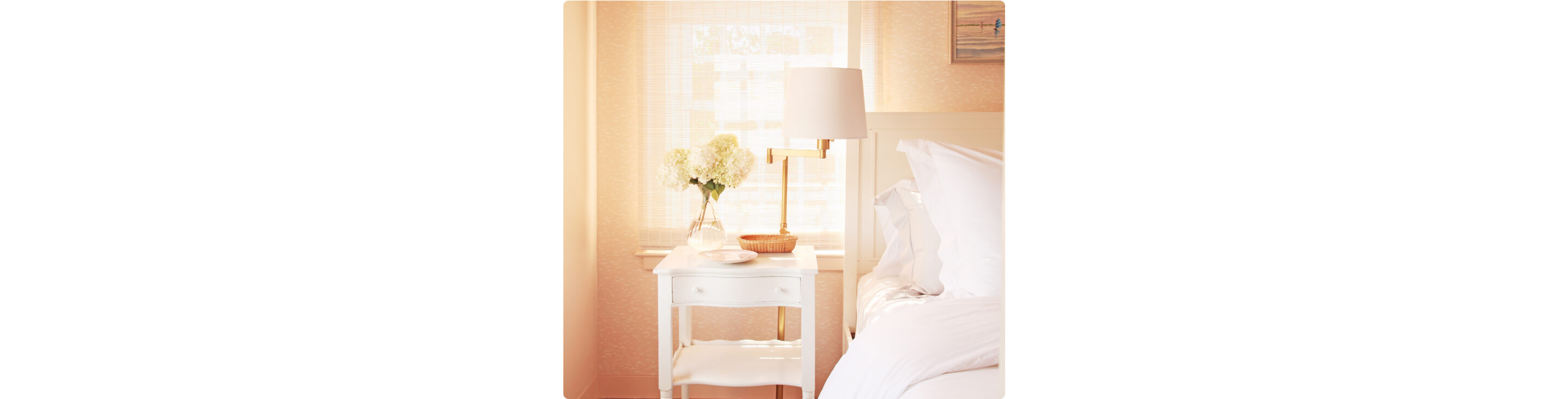 The nightstand decorated with hydrangeas and other dishes next to the bed. 