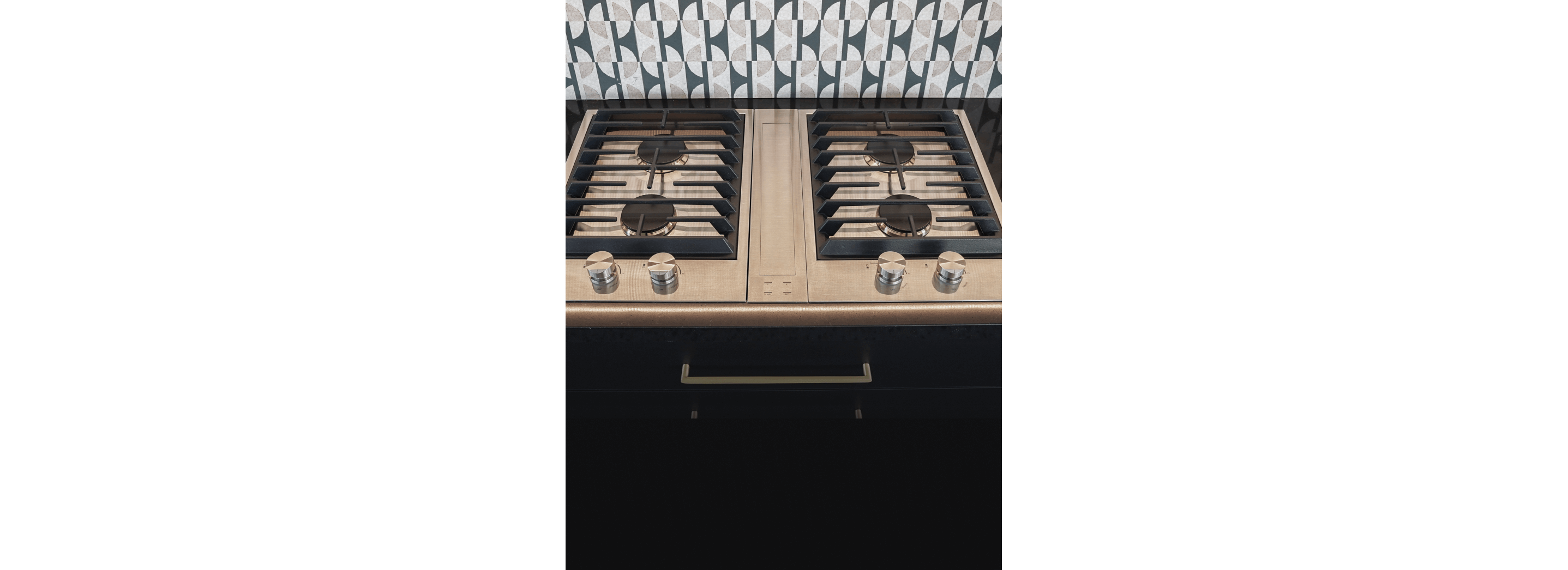 A close up on a pair of JennAir® Custom Cooktops with a Downdraft Ventilation Strip in the center.