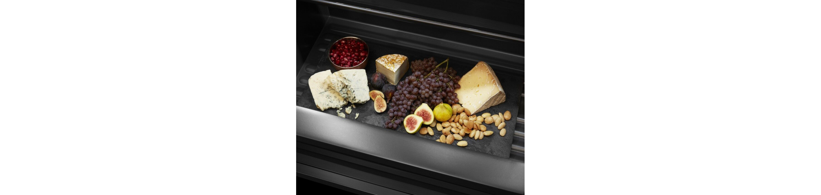 An open drawer filled with fruits and cheeses.