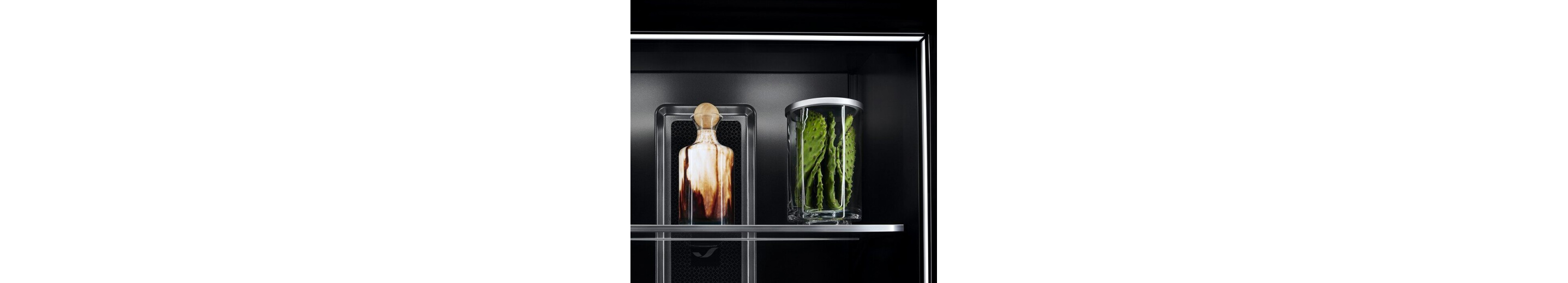 A close-up of shelves in a JennAir® Refrigerator, showing Ecliptic Lighting against the Obsidian Interior.