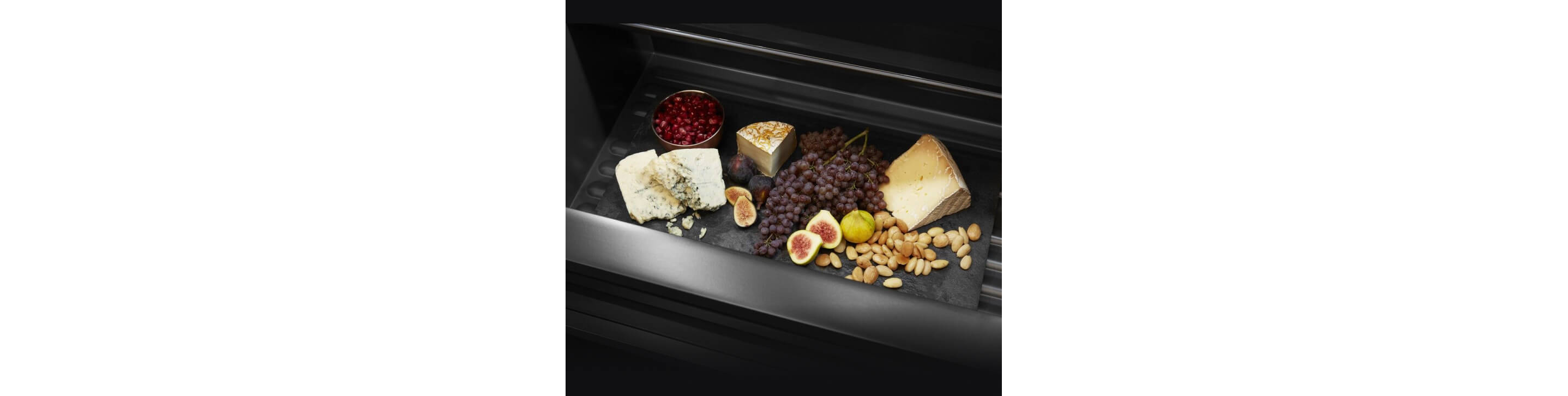 An open drawer filled with fruits and cheeses.