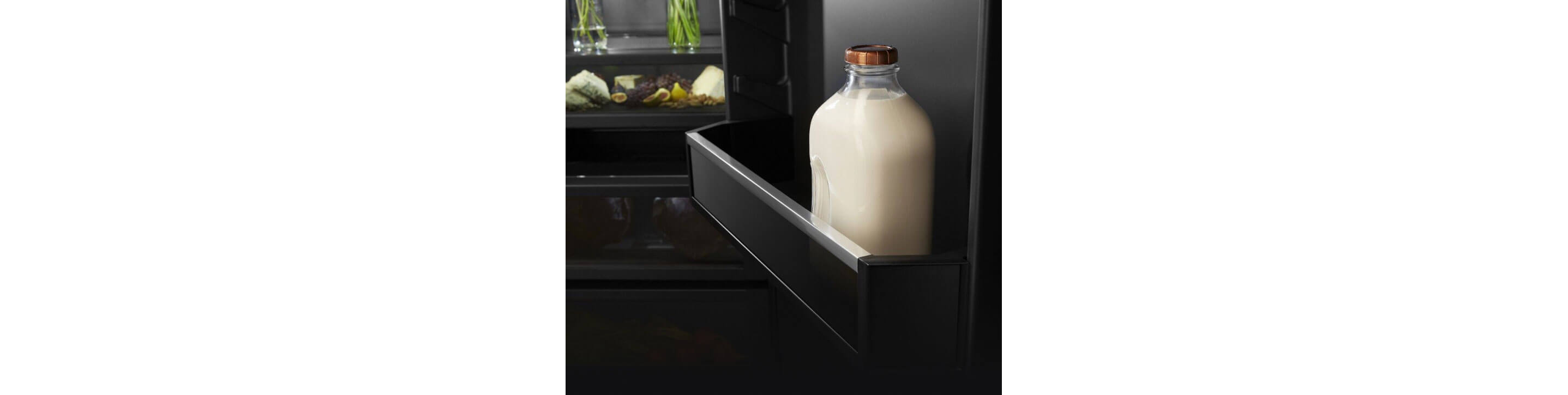 The door of a built-in refrigerator holding a glass gallon jug of milk.