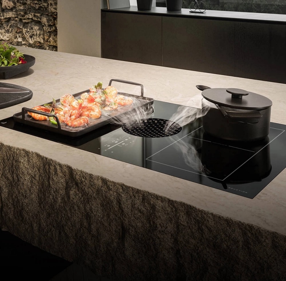 A downdraft cooktop pulling vapors in from two cooking pots.