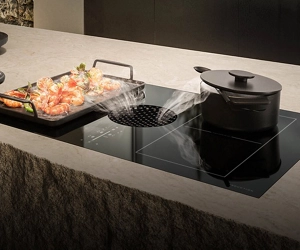 A griddle of shrimp cooking on a downdraft cooktop.