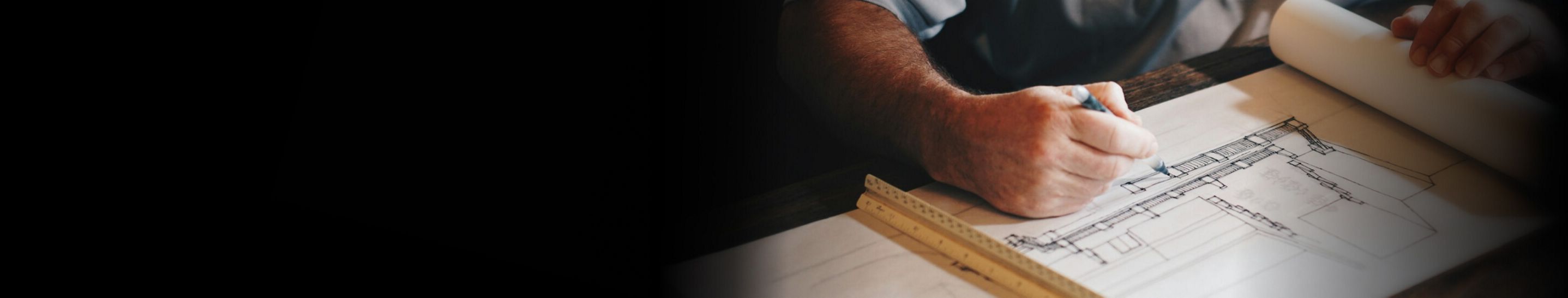 A person leaning over a set of architectural drawings.
