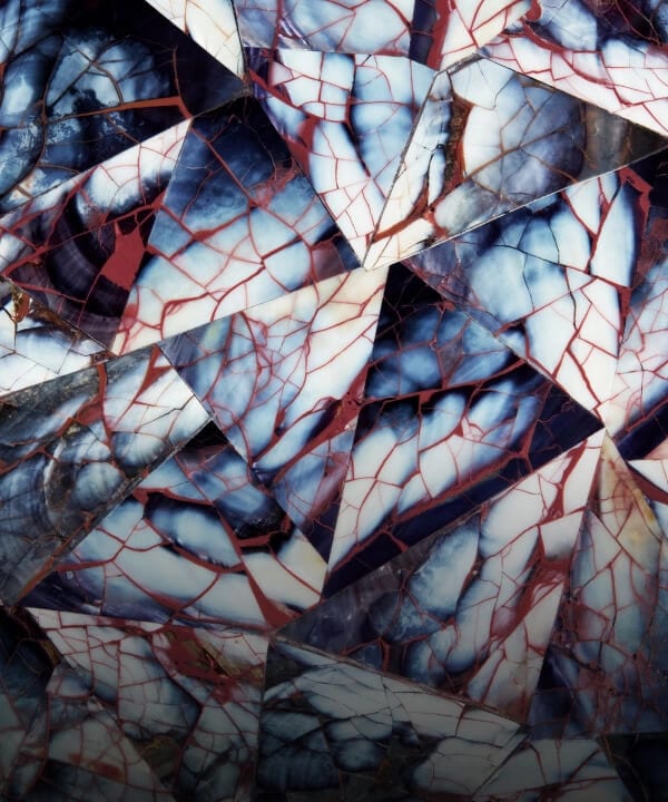 A triangular mosaic pattern made out of mussel shell, called Mussel Shell Burgundy.