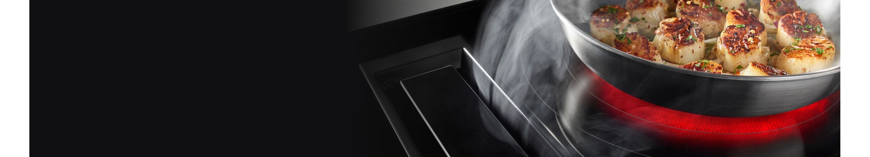 A JennAir Electric Downdraft Cooktop drawing steam from food cooking in a pan.