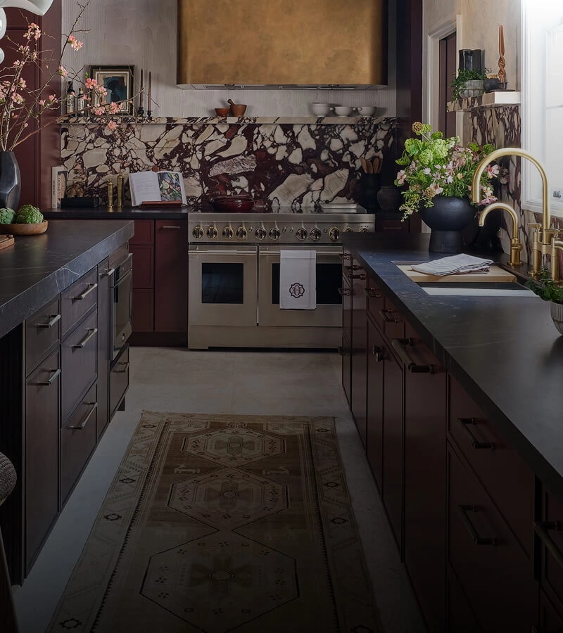 A stylish kitchen outfitted with maroon cabinetry and JennAir® appliances.