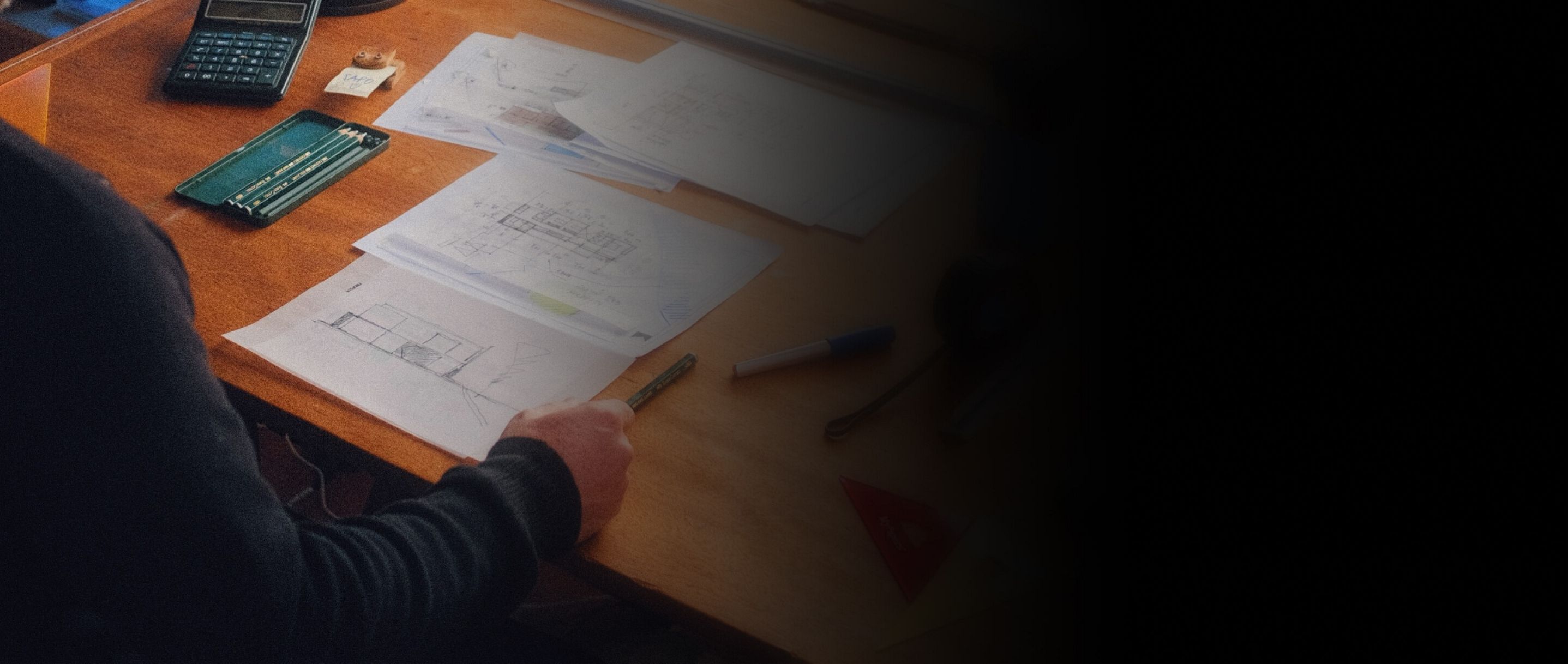 A person sitting at a workspace covered in architect's tools.